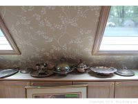 Full view of silverplate trays and serveware lined up, showing different sizes, shapes and covered pieces