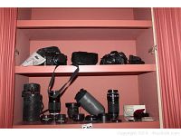 Overall display showing two Nikon SLR cameras on top shelf and multiple lenses/accessories on bottom shelf