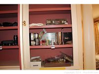 Shelf displaying various silver plate items including toothpick holders and napkin rings, along with glass barware and boxes.