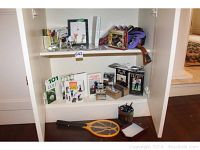 Wide shelf view showing golf books, golf instructional VHS tapes, golf balls, a golf award trophy, desk pen holder, notepad, an analog clock, and a purple carrying bag.