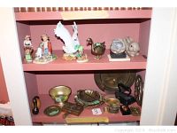 Shelf with Hummel and Norman Rockwell figurines, Mute Swan, brass ducks, and decorative plates