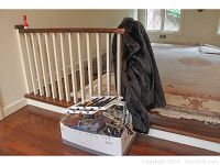 Photo showing dark brown short fur coat draped over a railing next to a box filled with various hangers.