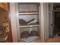 Cabinet shelf showing two brown Orvis felt hats, scarves on upper shelves, and Christian Dior pajamas in package beneath hats.