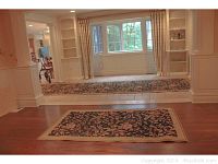 Photo showing the two rugs placed separately in rooms with hardwood and tiled floors, demonstrating the floral needlepoint style pattern and size.