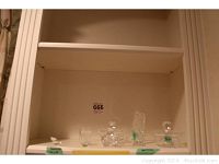 Shelf with Waterford crystal items including shot glass, sugar bowls, harp statue, and Swarovski pelican figurine
