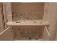 Top shelf displaying various stemware glasses including wine glasses and coupe glasses, arranged upright.