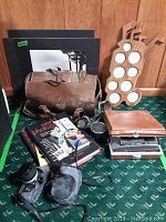 Various camera items laid out on green carpet including camera bag, books, golf ball display rack, filters, and camera accessories.