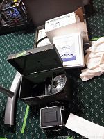 Photo showing Graflex camera with flash attached inside open black carrying case on carpeted floor.