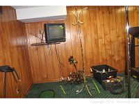 Chandelier and coat rack with wood paneling background, TV mounted on wall, various items on floor