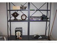 Wide shot of metal shelving in basement showing various kitchen and home items including coffee urn, basket, platter, boxes, clock.