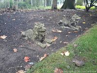 Front view showing two reclining lion statues positioned in a garden bed