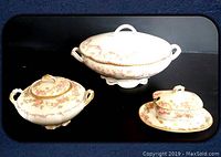 Front view of all items showing tureen, sugar bowl, and condiment dish with lids on black surface