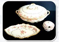 Image of 3 Limoges porcelain items: tureen with lid, bon bon dish, and mustard pot with lid on dark background.