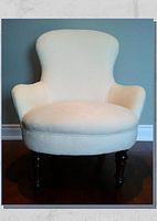 Front view of curved upholstered ladies chair with intricate textured fabric in light beige and dark wooden legs.