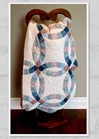 Quilt folded over top of wooden pine rack, showing pattern and scalloped edges