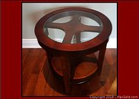 Top angled view of round coffee table with glass inset showing wooden base structure and lower shelf.