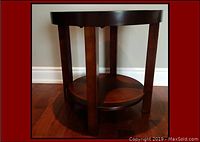Photo showing side view of the round wood coffee table with a lower shelf and four solid wood legs on a hardwood floor.