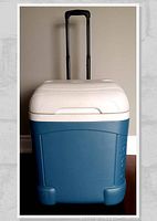 Front view of blue Igloo wheeled cooler with white lid and extended black telescopic handle.