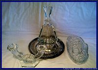Crystal decanter with stopper, double crystal candlestick holder, cut crystal bonbon dish and silver plated serving tray displayed side by side