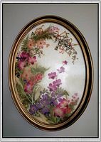 Full view of the oval framed pressed flowers artwork showing colorful floral arrangement of pink, purple and red flowers with greenery.