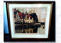 Full view of the framed watercolor painting showing a European waterfront scene with houses and their reflection on the water.