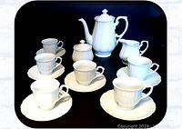 Full china tea set including teapot, creamer, sugar pot with lids, 6 cups and 6 saucers arranged on black background for display.