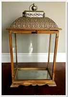 Front view of large indoor lantern with wooden frame, clear glass panels and silver filigree metal top