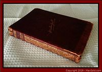 Photo showing the closed burgundy leather hardback book with gilt titling and some edge wear.