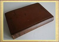 Book lying closed angled to show spine and front cover, light wear evident on spine ends and edges.