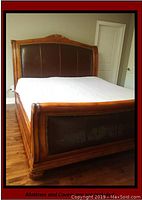 View of the king size bed frame showing the wood frame with leather upholstered headboard and footboard, upholstery tack trim visible, and overall condition with some wear.