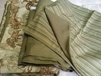 Folded toile pattern duvet cover alongside folded solid and striped sage green bedskirt pieces