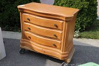 Wooden Hyundai dresser showing front view with three drawers and metal handles, sitting on a dolly.