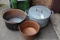 All three pots visible together: two copper pots and one large covered metal pot