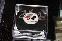 Black Team Canada hockey puck autographed by Steve Yzerman inside clear plastic case with name label