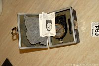 Antique durometer in open protective metal case with foam lining, showing device, instruction leaflet and interior details.