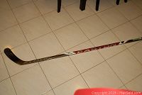 Full view of Easton Synergy hockey stick resting on tiled floor.