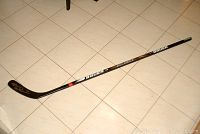 Full view of the Bauer Supreme 3030 hockey stick lying on tile floor, showing autograph on blade.