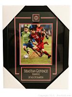 Frontal view of the autographed framed photo showing the full framing, autograph, and plaque.