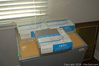 Three unopened packages of HealthGuard queen size microfiber sheet sets on top of a grey appliance.