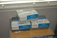 Three HealthGuard microfiber sheet sets in original packaging, piled on a table showing the overall lot condition and quantity.