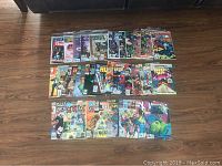Photo showing the full spread of 31 Marvel comics laid out on a wooden floor, featuring various characters and titles.