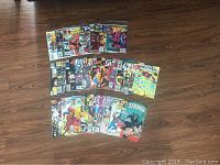 Photo showing 28 Marvel comic books laid out on a wooden floor with visible titles including Uncanny X-Men, Avengers, Dr. Strange, Nick Fury, and Marvel Premiere.
