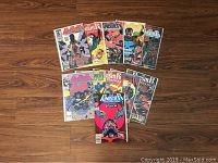 Photo of 11 Punisher comic books laid out on wooden floor, all in plastic sleeves. Shows front covers with various Punisher action scenes and characters.