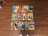 Multiple vintage comic books arranged in rows on a wood floor, featuring known characters such as Tom and Jerry, Chip and Dale, The Flintstones, and others.