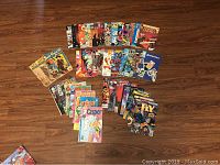 Photo showing a spread of various comic books laid out on a wooden floor.