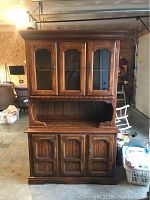 Full frontal view of the wooden buffet and hutch showing crown molding, glass doors, and cabinetry.