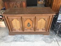 Exterior front view of the wooden stereo console showing carved panels and metal handle.