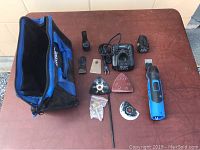 Multitool unit with charger, battery, five tool attachments, and carrying bag on table