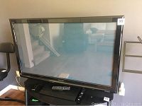 Front view of Panasonic plasma TV on stand with remote control visible