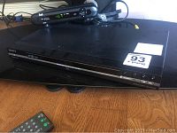 Sony black Precision Drive 3 DVD player on wooden surface with remote control partially visible.